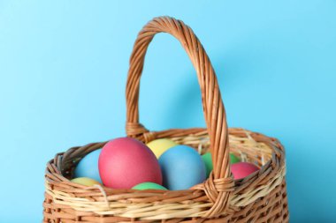 Açık mavi arka planda sepette güzel dekore edilmiş Paskalya yumurtaları, yakın plan.