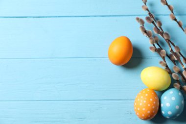 Güzel dekore edilmiş Paskalya yumurtaları ve söğüt dalları açık mavi ahşap masa üzerinde, düz uzanmış. Metin için boşluk