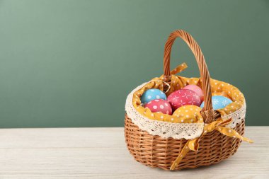 Birçok süslü Paskalya yumurtası ahşap masa üzerinde hasır sepetin içinde yeşil arkaplan, metin için boşluk