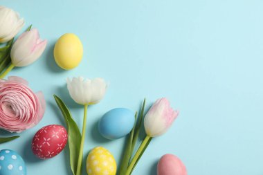 Paskalya yumurtaları ve açık mavi arka planda güzel bahar çiçekleri. Metin için boşluk