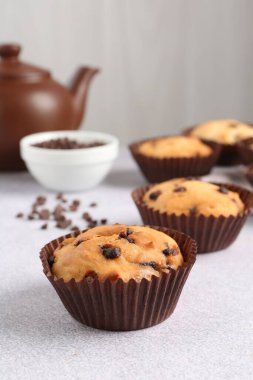 Açık gri masada çikolata parçalı lezzetli kek, yakın plan.