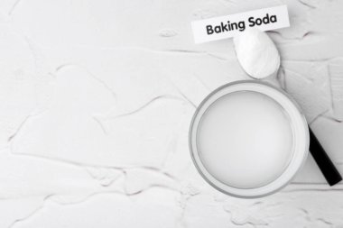 Beyaz desenli masa üzerinde su ve kabartma tozu olan bardak, üst manzara. Metin için boşluk