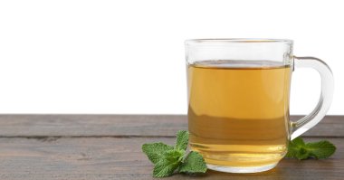 Cam fincanda aromatik nane çayı ve ahşap masada beyaz arka planda taze yapraklar, metin için yer