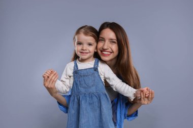 Mutlu anne portresi ve gri arka planda küçük tatlı kızı.