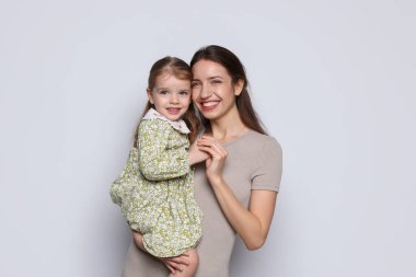 Mutlu anne portresi ve gri arka planda küçük tatlı kızı.
