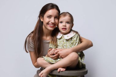 Mutlu anne portresi ve gri arka planda küçük tatlı kızı.