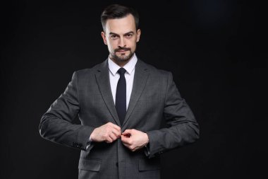 Siyah arka planda klasik takım elbiseli kendine güvenen bir adam.