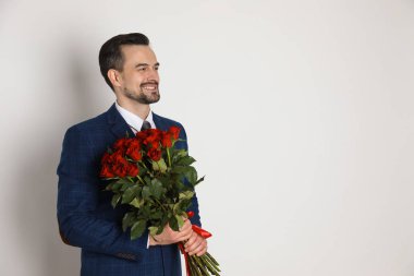 Sevgililer Günün kutlu olsun. Beyaz arka planda gül buketi olan yakışıklı bir adam. Metin için boşluk