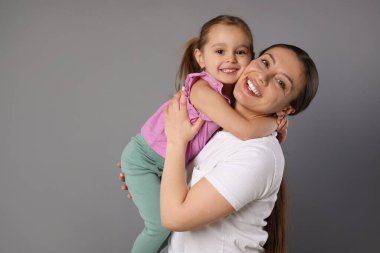 Gri arka planda mutlu anne ve tatlı kızının portresi.