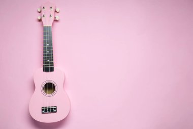 Pembe arka planda bir ukulele, üst manzara. Metin için boşluk