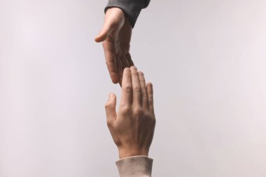 Açık gri arka planda arkadaşına yardım eli uzatan adam, yakın plan.