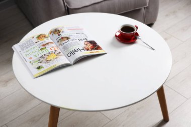 Bir bardak içki ve dergi, kapalı bir kahve masasında.