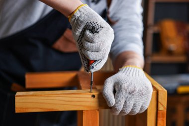 Marangoz atölyedeki ahşap tabureyi onarıyor.