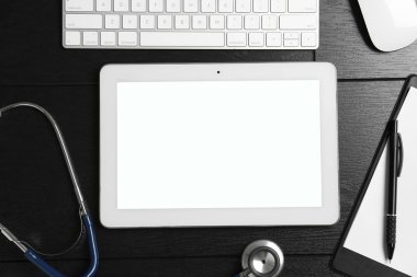 Kardiyoloji. Siyah ahşap masa üzerinde steteskop ve tablet ile düz kompozisyon