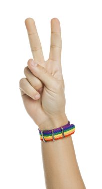 Beyaz arkaplanda barış işareti gösteren LGBT bayrağı renginde bileziği olan adam, yakın plan