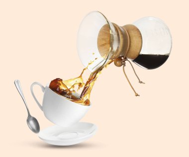 Cam kahve makinesinden taze demlenmiş kahveyi pembe bej arka planda fincana döküyorum.