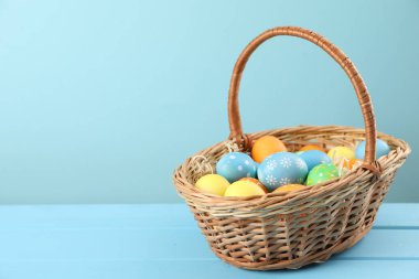 Birçok süslü Paskalya yumurtası sepette açık mavi ahşap masa üzerinde, metin için yer var.