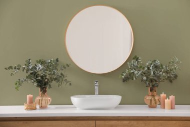 Şık bir ayna, okaliptüs dalları ve modern banyoda batan bir kap. Adaçayı rengi ile iç tasarım