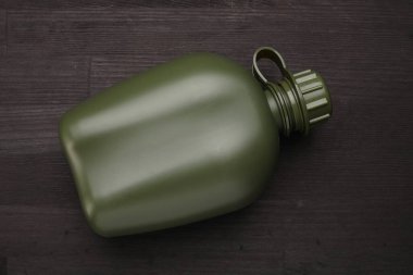 Ahşap masanın üstünde yeşil plastik matara, üst manzara.