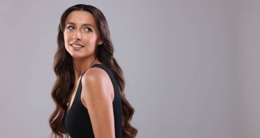 Saç şekillendirme. Gri arkaplanda dalgalı uzun saçlı güzel bir kadın, mesaj için boşluk.