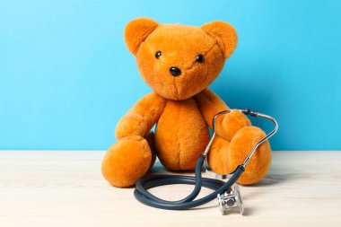 Pediatri konsepti. Masada steteskoplu oyuncak ayı açık mavi arka planda