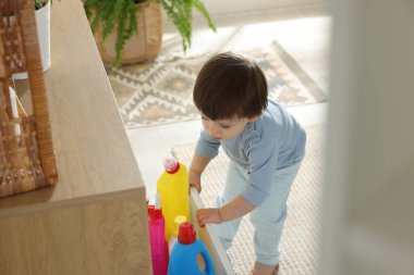 Küçük çocuk evde deterjan şişeleriyle çekmece açıyor. Çocuk tehlikede.