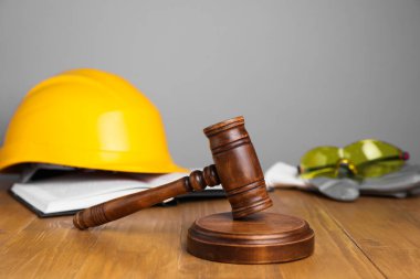 İş yerinde kaza oldu. Gavel, kitap ve inşaat işçilerinin koruyucu giysileri ahşap masada, seçici odaklı.
