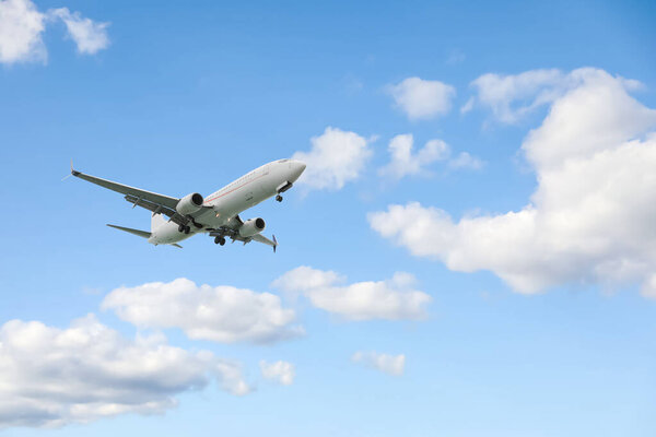 Самолет летит в красивом голубом небе с облаками