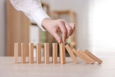 Masada tahta blokların düşmesini engelleyen kadın, yakın plan. Domino etkisi