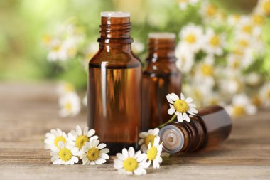 Ahşap masada gerekli yağ ve papatya çiçekleri, yakın plan.