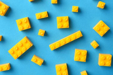 İnşaat oyuncağı. Açık mavi zemin üzerinde birçok sarı yapı taşı düz yatıyordu.