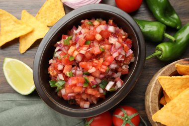 Tabakta nefis salsa, cips ve ahşap masada malzemeler.