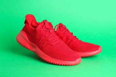 Yeşil arka planda bir çift şık kırmızı spor ayakkabı.