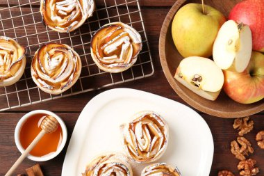 Ahşap masada servis edilen pudra şekerli lezzetli elma gülleri.