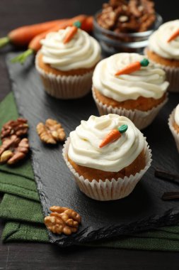 Kremalı havuçlu kekler ve siyah ahşap masada cevizler, yakın plan.