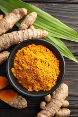 Akvaryumdaki Aromatik zerdeçal tozu, taze kökler ve ahşap masa üzerindeki yapraklar, düz uzanmış.