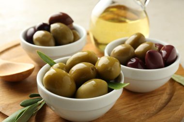 Lezzetli marine edilmiş zeytinler kaseler, kaşık, yağ ve yeşil yapraklar masada, yakın çekim