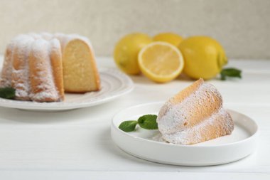 Lezzetli limonlu kek, pudra şekeri ve nane şekeri beyaz ahşap masada.