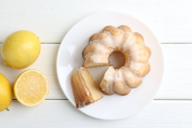 Lezzetli limonlu kek ve beyaz ahşap masada narenciye meyveleri, düz yatıyordu.