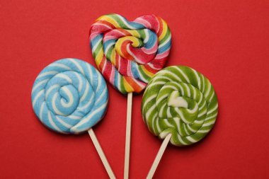 Kırmızı arka planda lezzetli lolipoplar, düz yatış