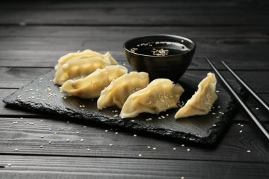 Lezzetli haşlanmış gyoza (hamur tatlısı) siyah ahşap masada servis edilir, yakın plan.