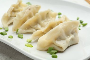 Lezzetli haşlanmış gyoza (hamur tatlısı) ve yeşil soğanlı beyaz masa, yakın plan