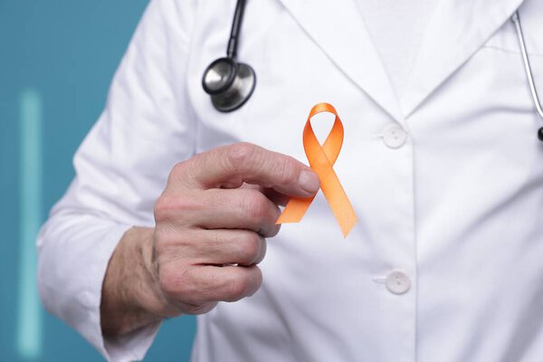 Multiple Sclerosis awareness. Doctor with orange ribbon on light blue background, closeup