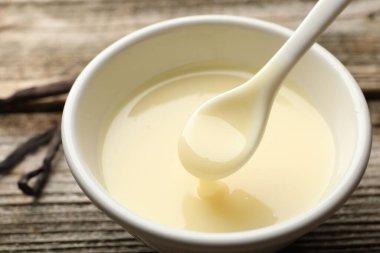 Lezzetli vanilyalı yoğurtlu sütü ahşap masadaki kaşıkla yakın plan çekiyoruz.