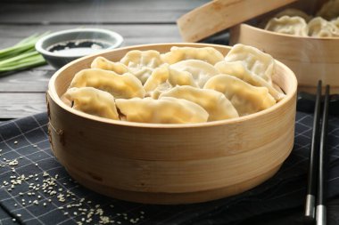 Lezzetli haşlanmış gyoza (hamur tatlısı) siyah ahşap masada servis edilir, yakın plan.