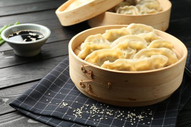Soya soslu haşlanmış gyoza (hamur tatlısı) ve siyah ahşap masada susam.