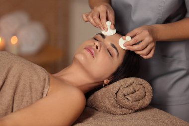 Genç bir kadın güzellik salonunda yüz masajı yaptırıyor.