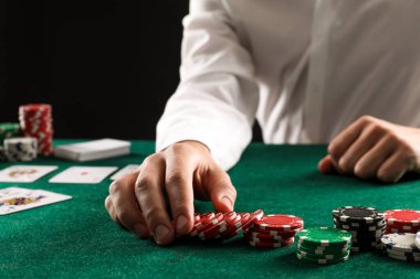 Kumar masasında poker oynayan kart ve kumarhane fişleri olan adam, yakın plan.
