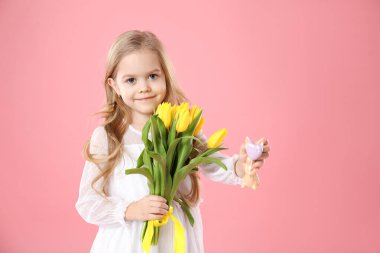 Sarı laleleri ve pembe arka planda dekoratif tavşanı olan sevimli küçük bir kız. Paskalya kutlaması