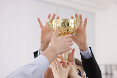 Rekabet konsepti. Ofisinde altın kupa olan bir grup iş adamı, yakın plan.